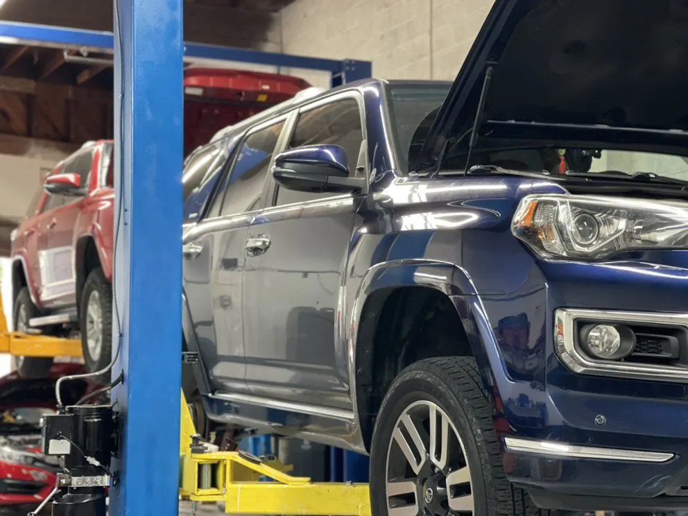 An SUV on the lift with the hood open, seen up close
