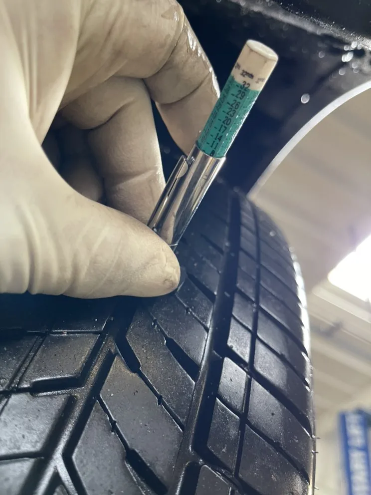 A tread depth gauge being used on a tire